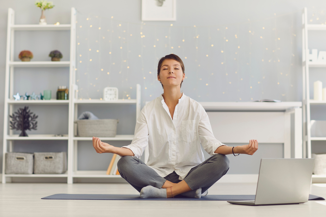 Woman Meditating in the Workplace Sitting in Front of a Laptop Practicing Stress Relief Exercises.